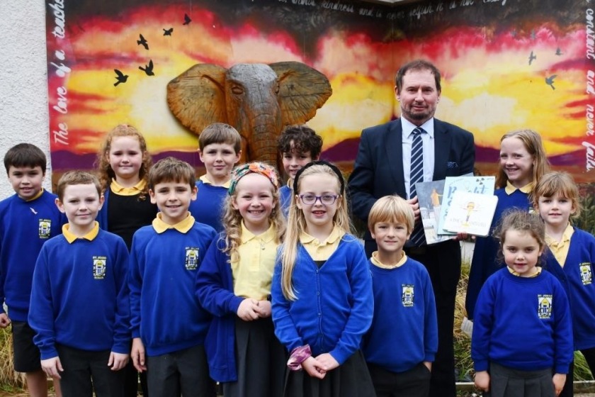 Minister Boot, at St John's Primary School, presenting three of the SDG Book Club series to representatives of the school's council.